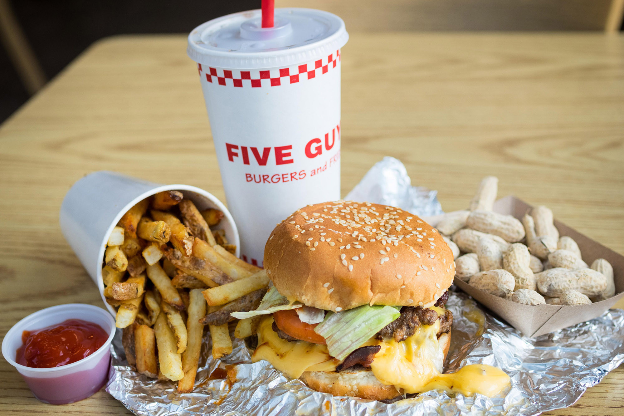 A bacon cheeseburger, French fries, and peanuts from Five Guys Burgers and Fries, an American fast casual restaurant chain.