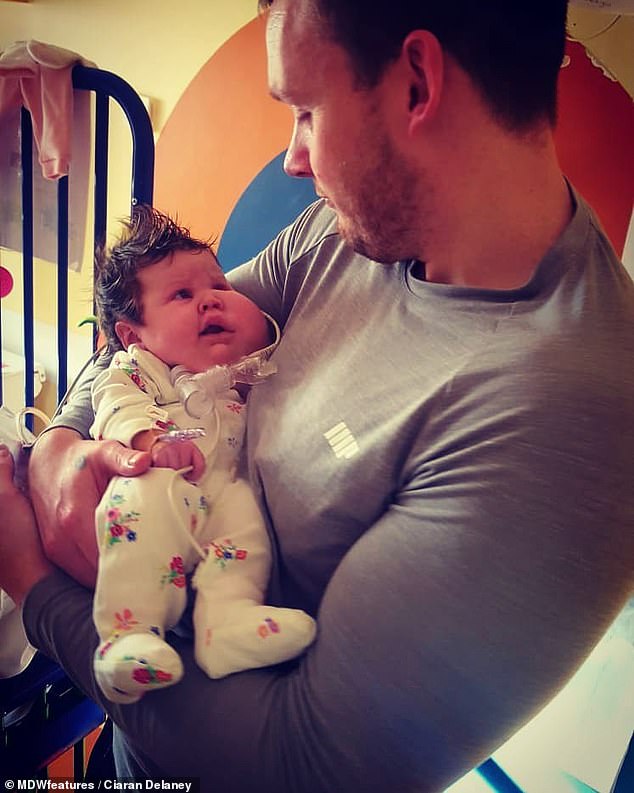 Recalling the moment they discovered they were expecting a child, Mr Delaney said: 'We found out when we got home and we were delighted' Mr Delaney is pictured holding Evie in hospital