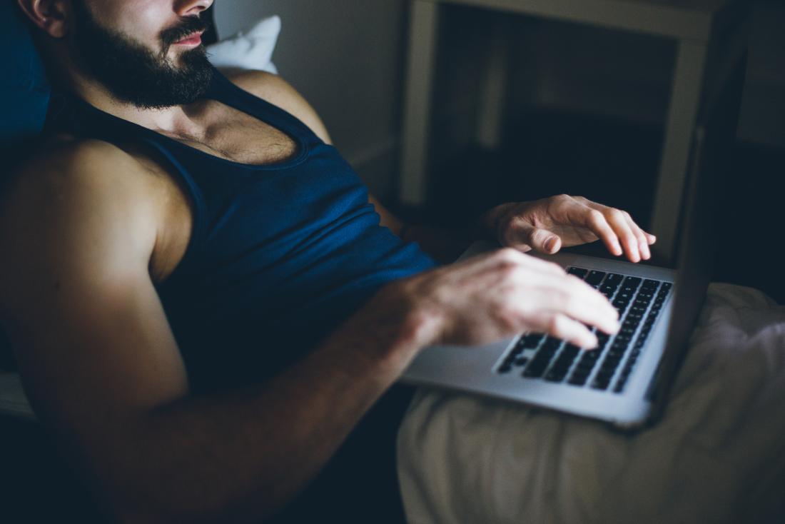 Man using his laptop in bed