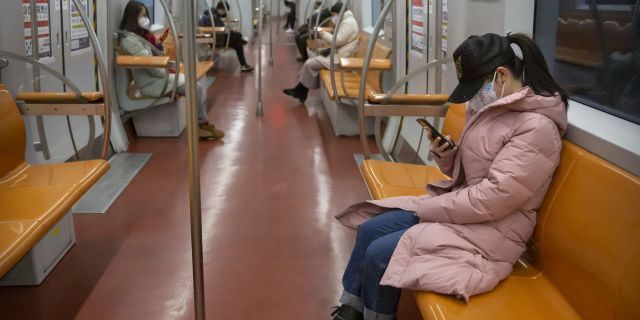 People wearing face masks ride a mostly empty subway train during the morning rush hour in Beijing, Monday, Feb. 3, 2020.  (AP Photo/Mark Schiefelbein)